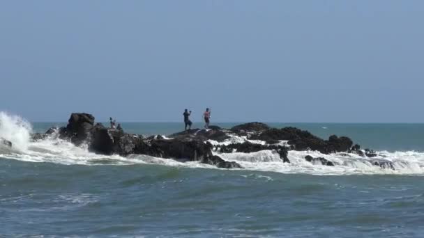 Vagues Éclaboussant Les Rochers Tandis Que Certaines Personnes Essaient Prendre — Video