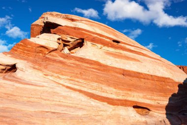 Parlak turuncu gün batımı ışığı ateş vadisinde ve kayalarda parlıyor.