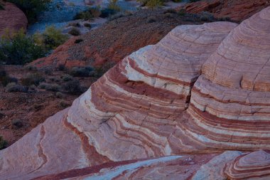 Ateş Vadisi 'ndeki pembe, mor ve parlak renkli çizgilerle karışık kayaların tepesinden bak. 