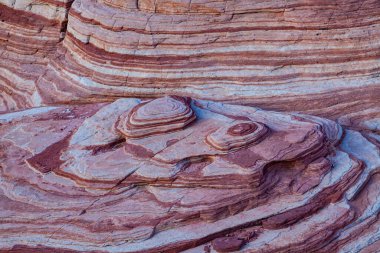 Ateş Vadisi 'ndeki pembe, mor ve parlak renkli çizgilerle karışık kayaların tepesinden bak. 