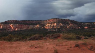 Kayalık dağlarla, kum ve kara fırtınalı bulutlarla dolu doğa manzarası.