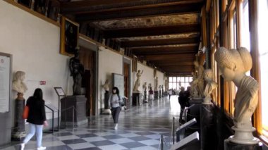 Uffizi Galerisi koridorunun içi ve turistlerin sanat ve heykellere baktığı görüntüler. Floransa, İtalya. 