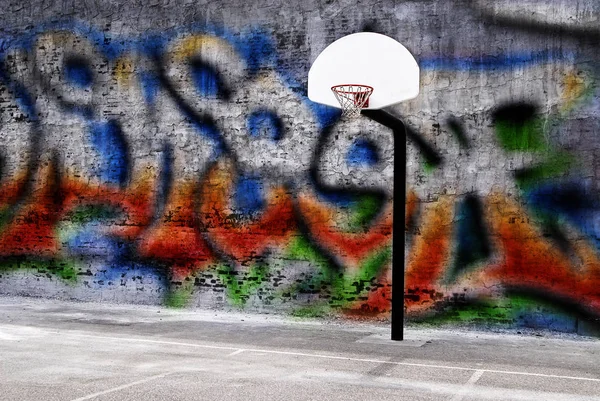 Detail of urban basketball hoop inner city innercity wall and asphalt in outdoor park graffitti