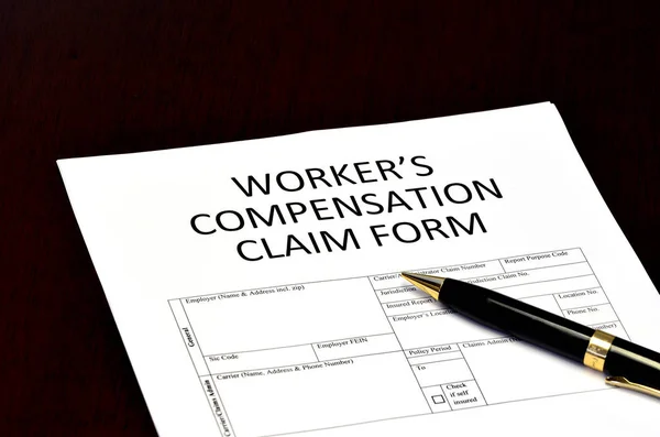 Worker's compensation claim form application with pen on desk