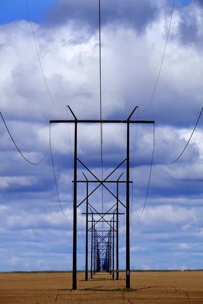 Powerlines-ban mező-val kék ég és felhők — Stock Fotó