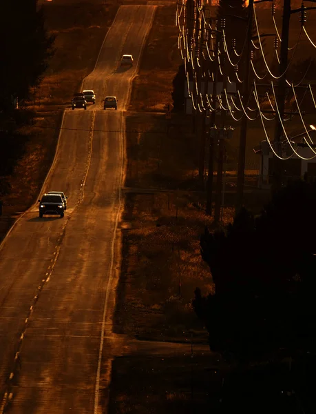 日没または日の出時に郡道を運転する車 — ストック写真