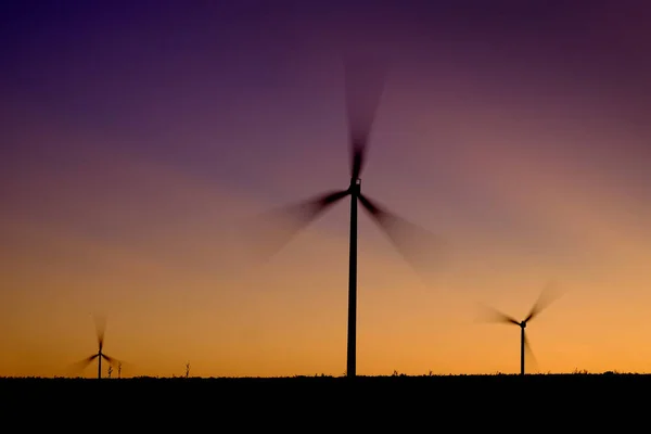 风车风力涡轮机在日落或日出时在风中旋转 — 图库照片
