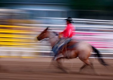 Kovboy rodeo arenasında hızlı ve bulanık hızda ata biniyor.