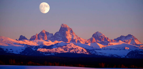 Sunset light with alpen glow on Tetons Tetons mountains rugged with moon rising
