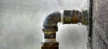 Sızıntı ve su püskürten eski paslı bir boru.