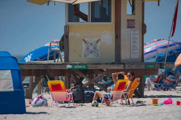 Pessoas na praia sentadas perto da torre do salva-vidas — Fotografia de Stock