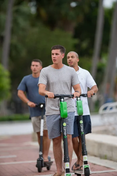 Young men riding rental scooters on Las Olas Riverwalk — Stock Photo, Image