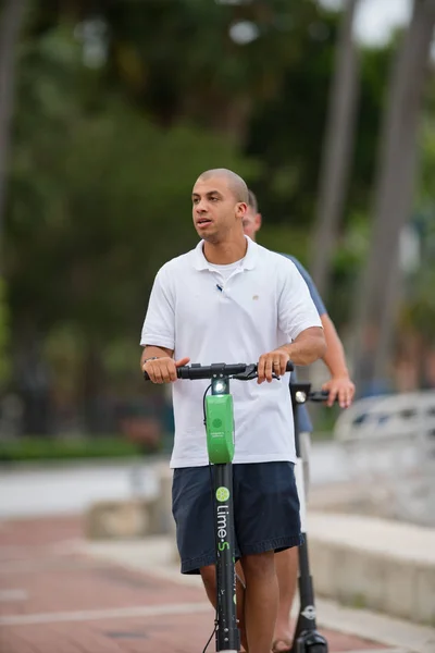 Young men riding rental scooters on Las Olas Riverwalk — Stock Photo, Image