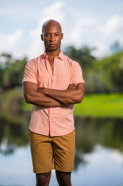 Man posing in a pink button shirt with arms crossed. African Ame clipart