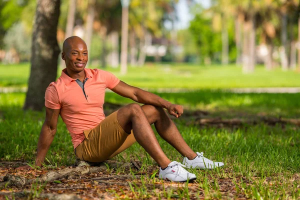 Foto van een jonge zwarte man zittend in het Park. Persoon die c draagt — Stockfoto