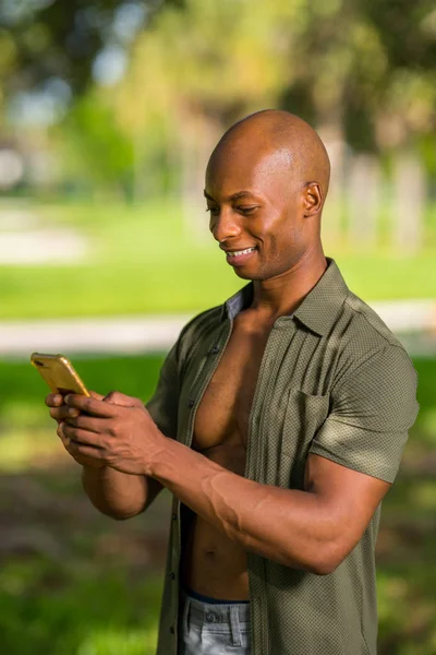 Фото красивого чернокожего мужчины, отправляющего смс-ку на своем смаре — стоковое фото