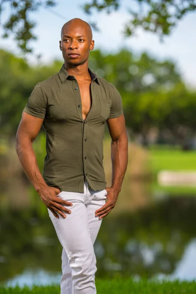 Foto de um homem bonito posando com as mãos nos bolsos em um parque s — Fotografia de Stock