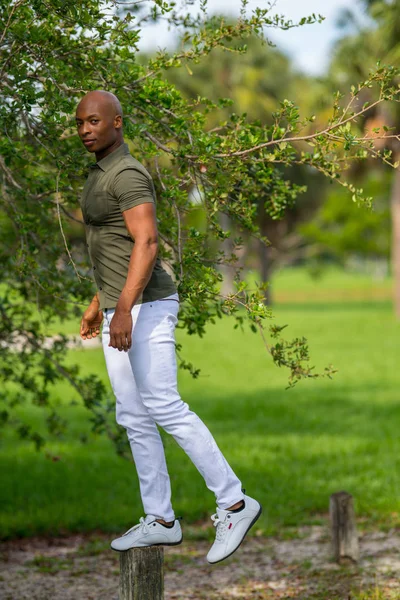 Foto de um homem bonito balanceando em um post em uma cena do parque — Fotografia de Stock