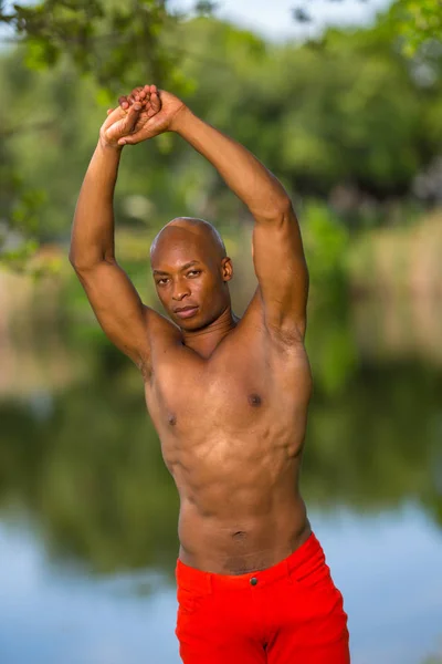 Foto de un joven modelo de fitness afroamericano estirándose en th —  Fotos de Stock