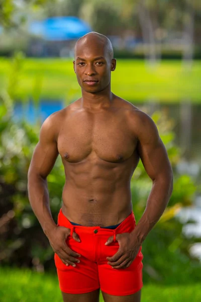 Handsome shirtless male fitness model posing in the park. Blurry — Stock Photo, Image