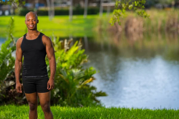 Hombre sonriente posando junto a un lago en el parque. Lit con cámara apagada fl —  Fotos de Stock