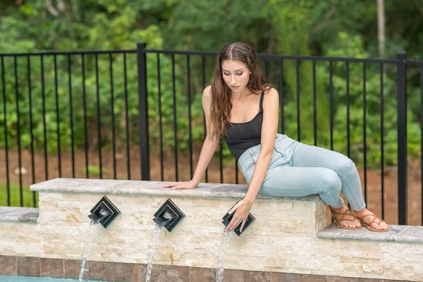 Femme touchant l'eau sortant de la fontaine de la piscine — Photo