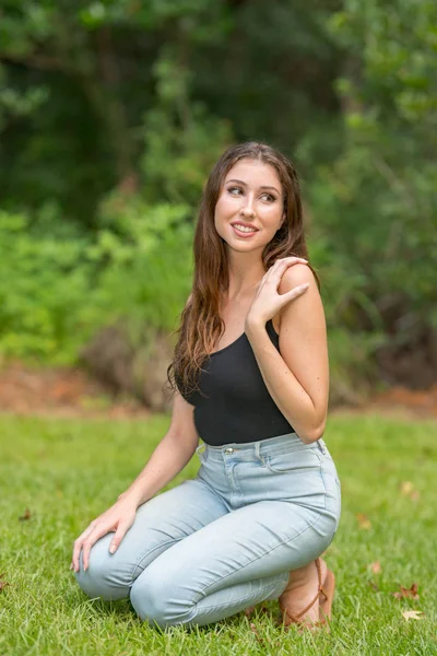 Bir çömelme poz mutlu genç kadın doğa sahnesi gülümseyen — Stok fotoğraf