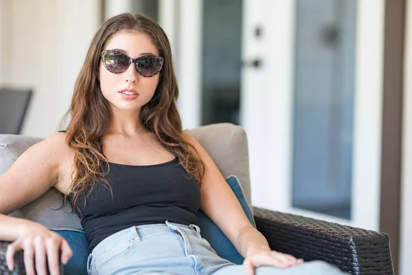 Beautiful woman with vintage sunglasses sitting on a chair — Stock Photo, Image
