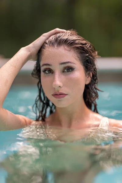 Model bikini pozowanie w basenie z ręką na głowie — Zdjęcie stockowe