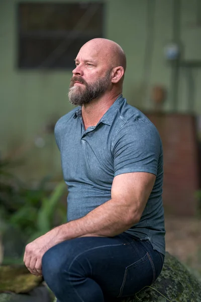 Bel homme chauve mature avec barbe grise assis regardant loin fr — Photo