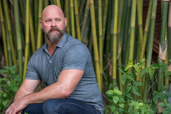 Photo of a handsome mature bald man with beard. Man is squatting — Stock Photo, Image