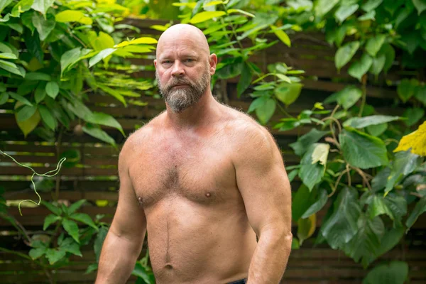 Красивий зрілий чоловік позує в саду без сорочки — стокове фото