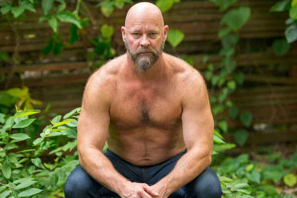 Mature man posing with no shirt in a garden scene — Stock Photo, Image