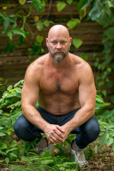 Homem sem camisa posando no jardim. O homem está na casa dos 50 com careca. — Fotografia de Stock