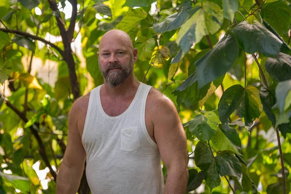 Schöner Mann posiert im Freien in einem Garten mit grünen Blättern — Stockfoto