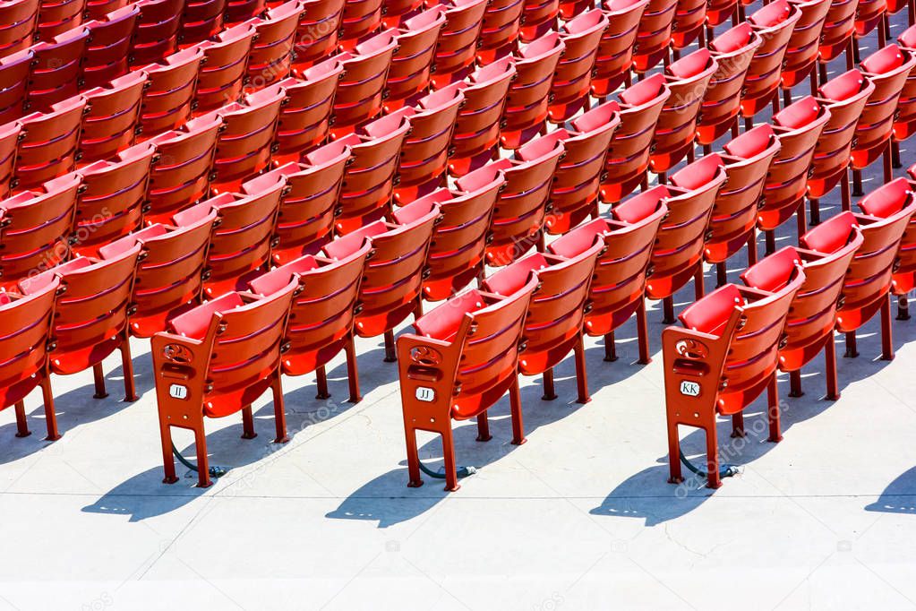 Numbered rows of red plastic seats in an outdoor theatre, rear side landscape view