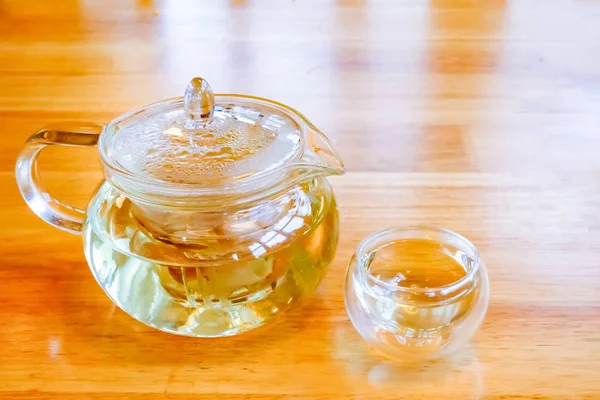 Brightly lit glass teapot and cup on a wood table in China