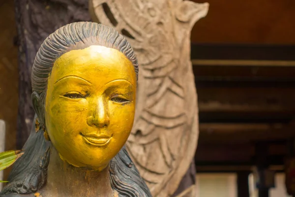 Gilding on the face of wooden female sculpture in Lamphun, Thailand
