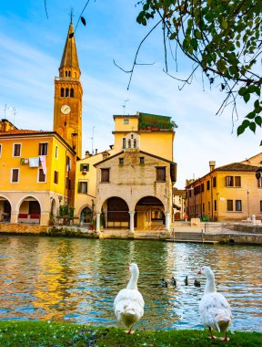 Vertical view of Lemene river, clock tower and Oratorio Madonna della Pescheria, Portogruaro, Veneto, Italy clipart