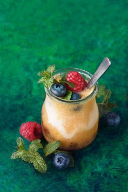 Mango, yoğurt, yaban mersini ve ahududu yeşil zemin üzerine taze yüzlü