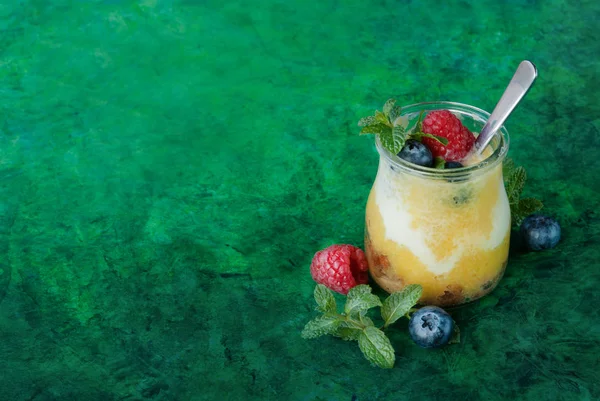 Mango, yoğurt, yaban mersini ve ahududu yeşil zemin üzerine taze yüzlü