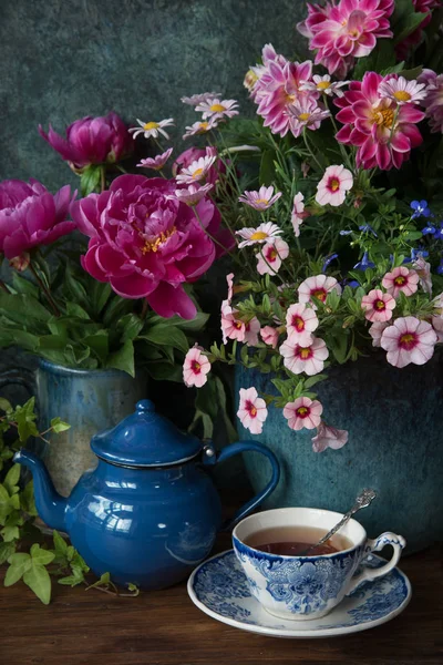 美丽的花朵在花瓶和杯茶在木桌 夏季装饰 — 图库照片