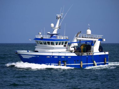Modern trawler underway at sea to fishing grounds. clipart