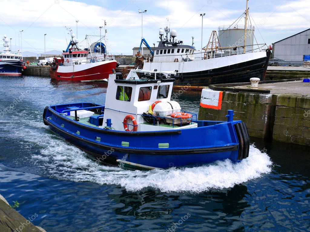 Harbour workboat underway at speed to assist boats.