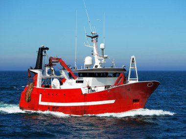 Red fishing boat underway at sea to fishing grounds. clipart