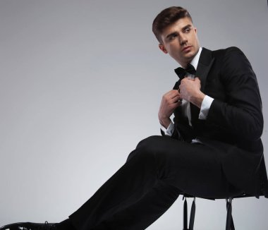 zarif yakışıklı genç sabitleme uymak yaka ve açık gri renkli metal bir sandalyede otururken tarafına bakarak portre