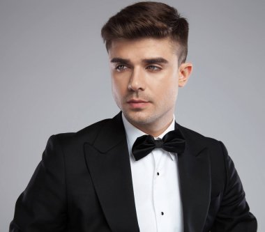 siyah smokin yan seductively üzerine açık gri renkli için seyir yakışıklı genç adam portresi