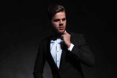 isteyen yan duran siyah arka plan üzerine siyah bir smokin giyiyor düşünceli zarif adam portresi