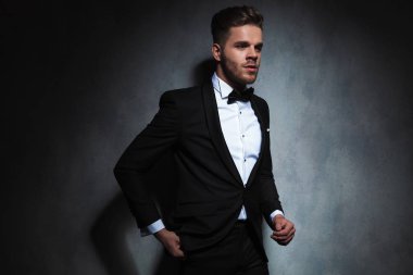 zarif adam yan cebinde bir el ile siyah duvar kağıdı yakın dururken görünüyor