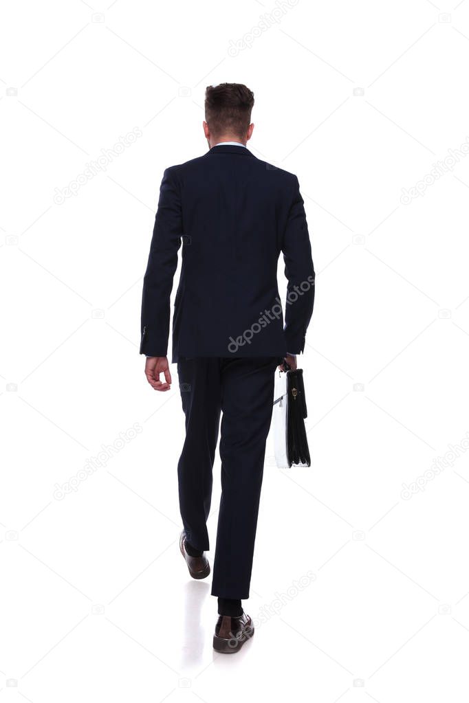 back view of stepping businessman in navy suit with briefcase in hand on white background, full body picture